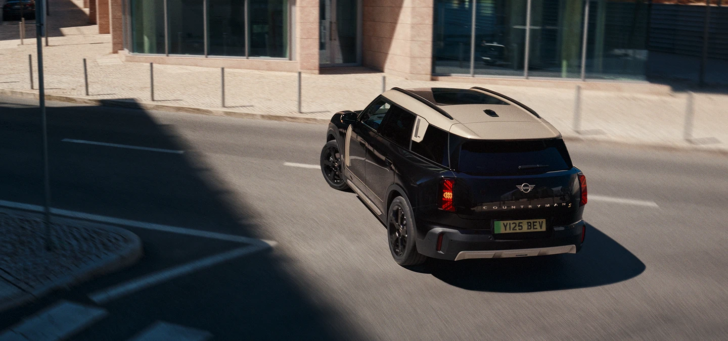 Rear top view of the all-electric MINI Countryman in Midnight Black with Vibrant Silver Roof parking,