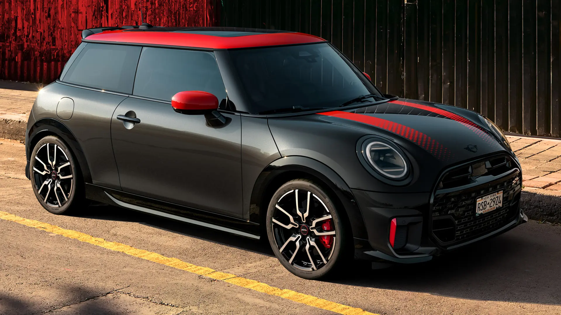 MINI John Cooper Works 3-door in Midnight Black with roof and mirror caps in Chili Red and sport stripes red, side view, parked in street.