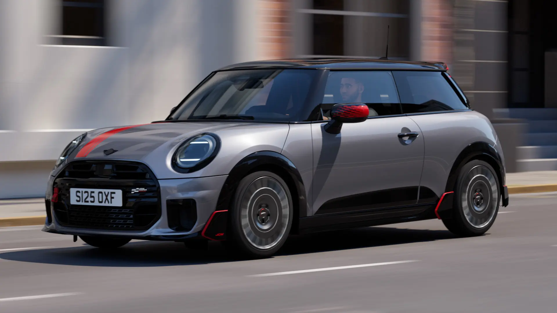 MINI Cooper 3도어 (멜팅 실버), 존 쿠퍼 웍스 미러 캡 및 보닛 데칼 (칠리 레드), 루프 스포일러 및 윙렛 (블랙), 도시 도로를 따라 달리는 모습 - 전면 전망.
