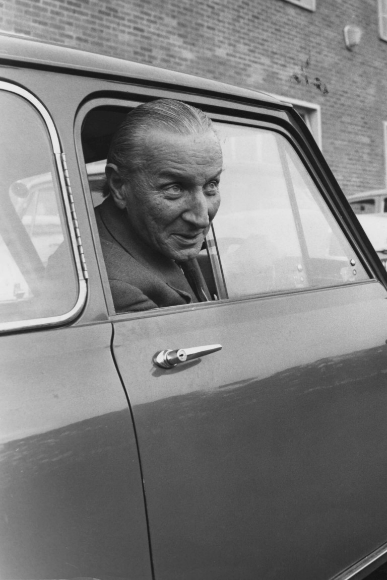 Sir Alec Issigonis sitting inside a Mini.