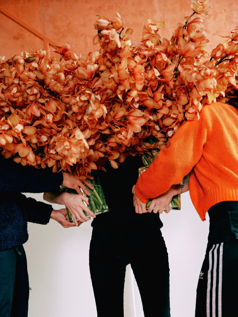 Ruby’s assistants hand her large vases of orchids. 